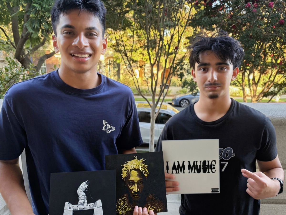 Two people holding three 3D printed album covers